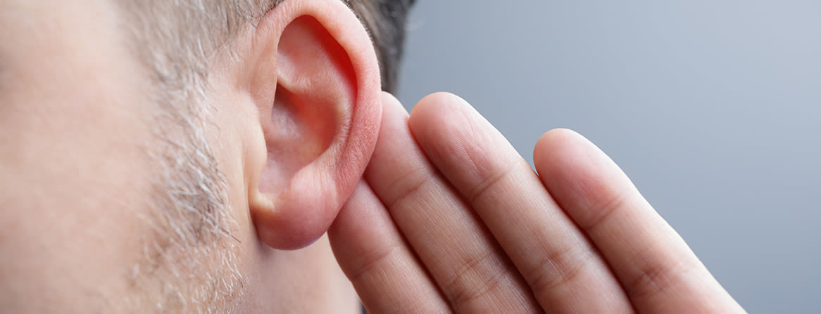 Mann lytter nøye med hånden ved øret.