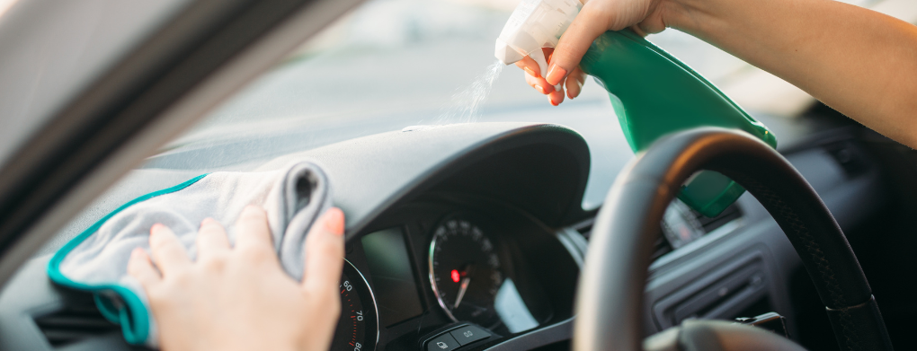 Rengjøring av bilens dashbord med rengjøringsspray og mikrofiberklut