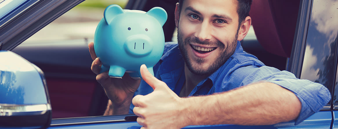 Smilende mann i bil holder en blå sparegris og gir tommel opp.