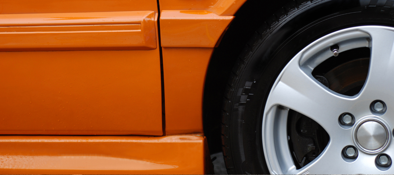 Nærbilde av bildekk på en oransje bil.