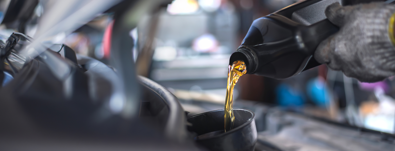 Motorolje helles fra svart kanne ned i bilens motor.